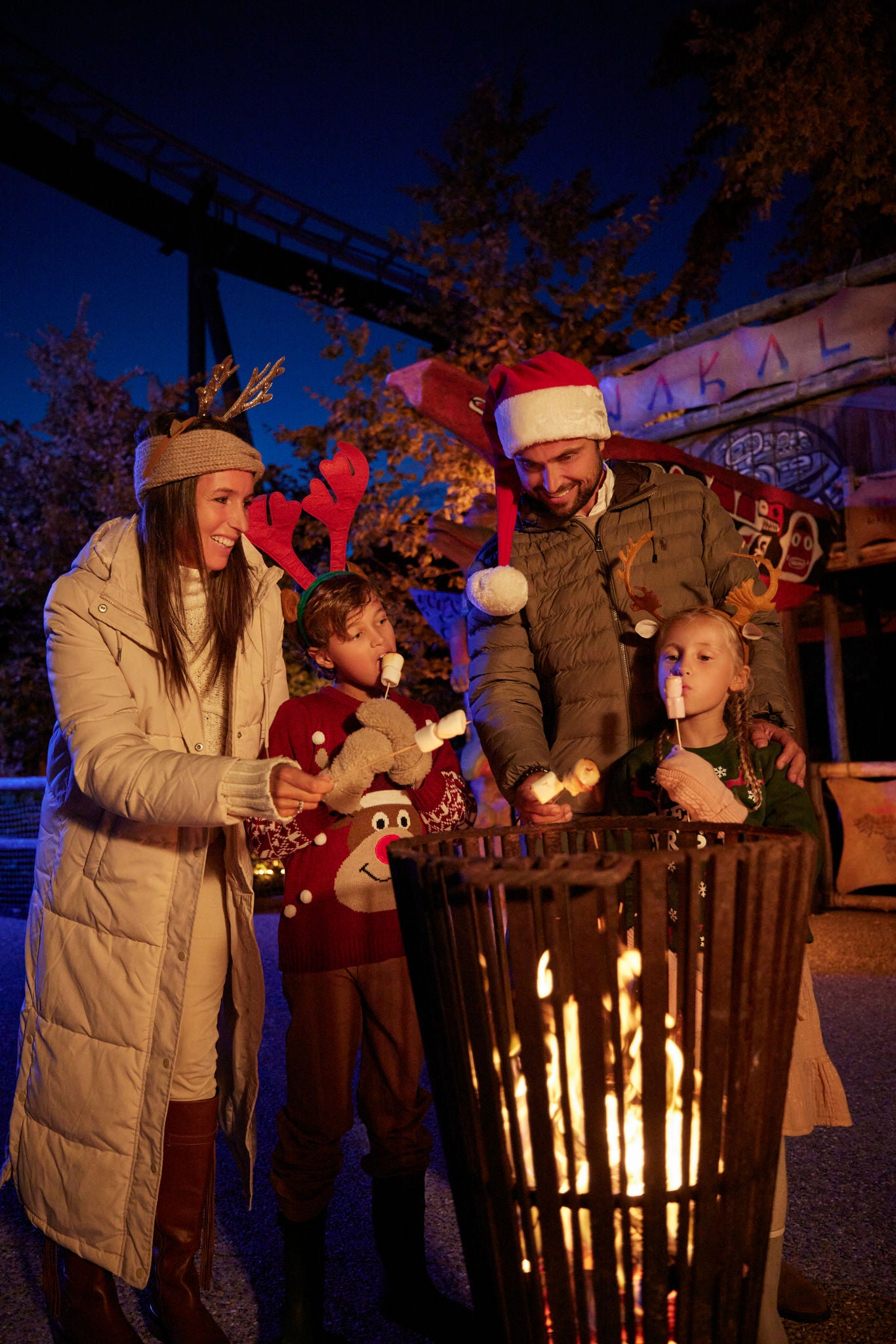 Gezin verwarmt marschmallows boven een vuurkorf tijdens Kerst.