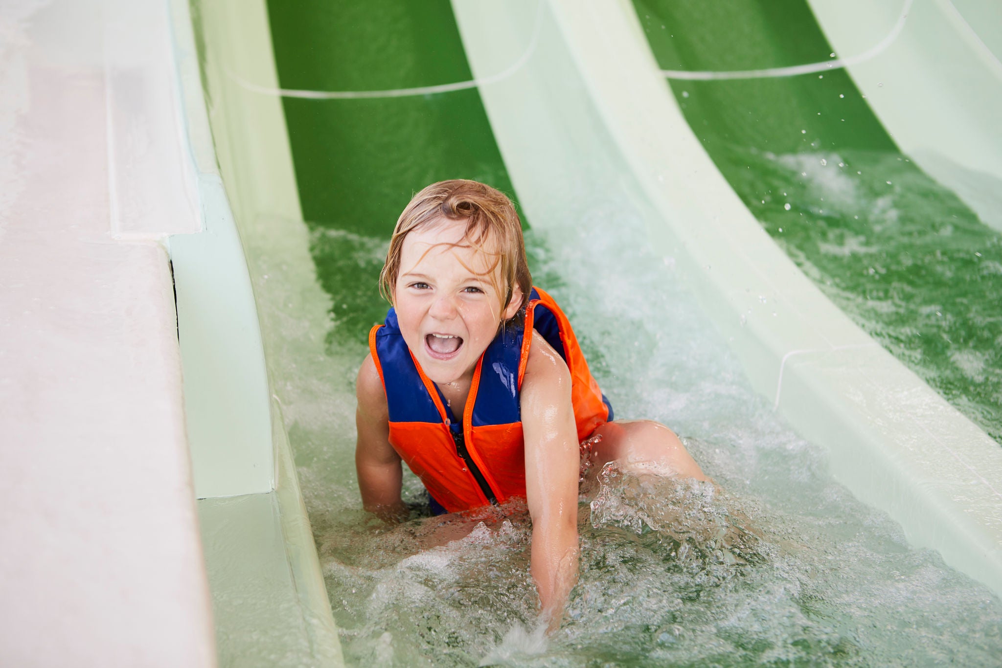 Jongen glijdt van de glijbaan van Bambino Beach.