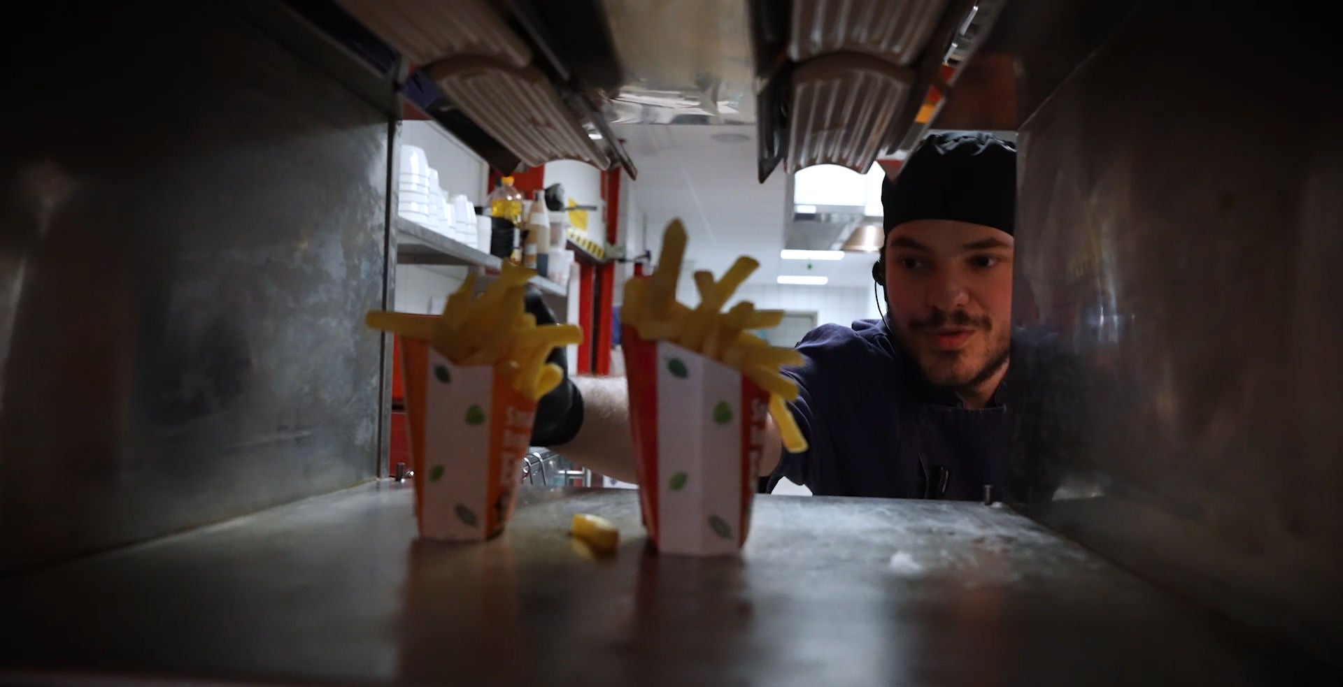 Evan neemt een bakje friet uit de keuken.