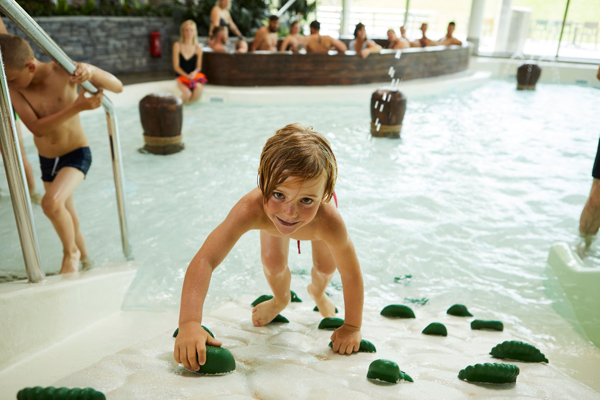 Jongen klimt omhoog op de klimmuur van Bambino Beach.