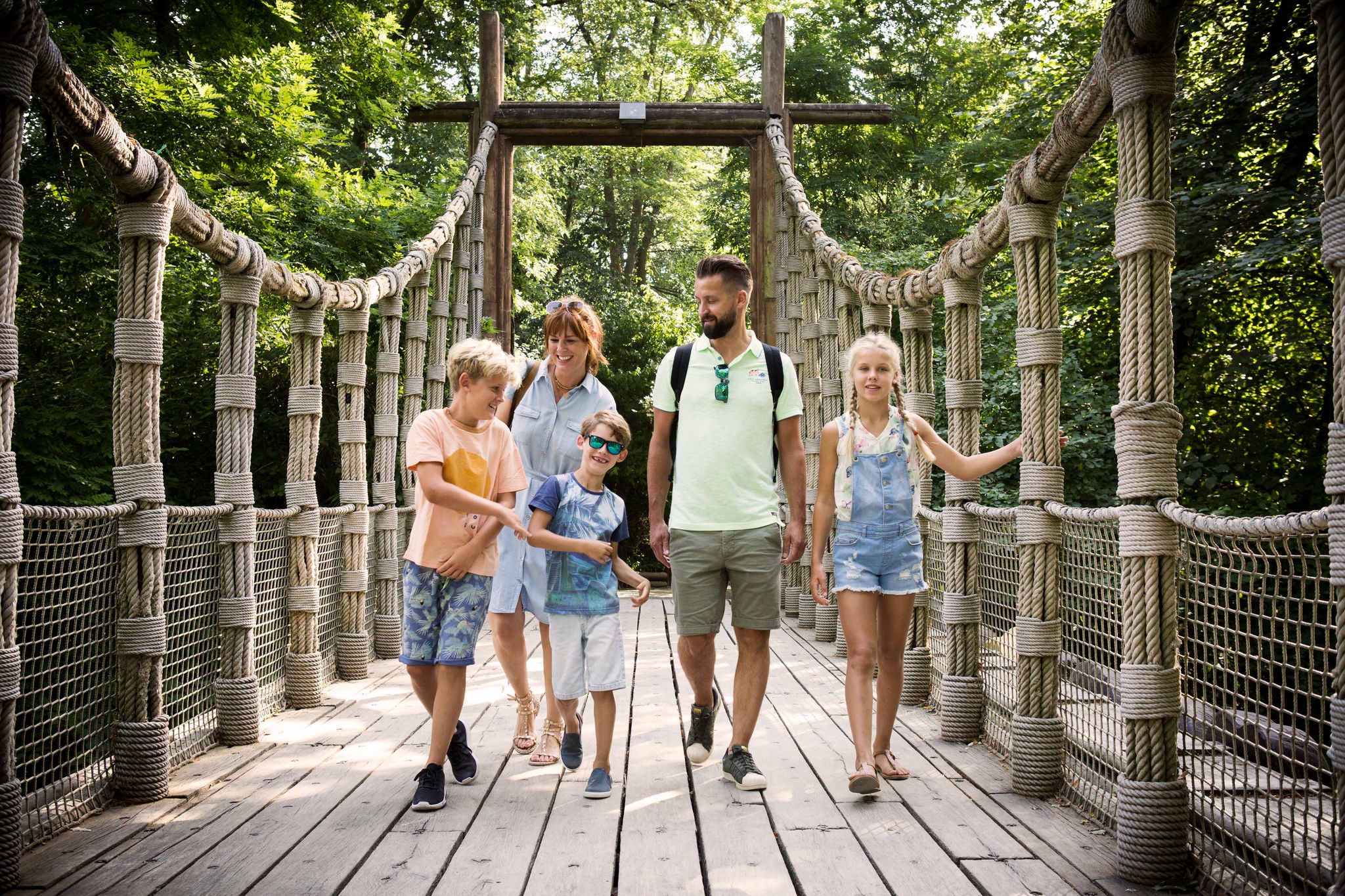 Gezin wandelt op een brug doorheen de jungle.