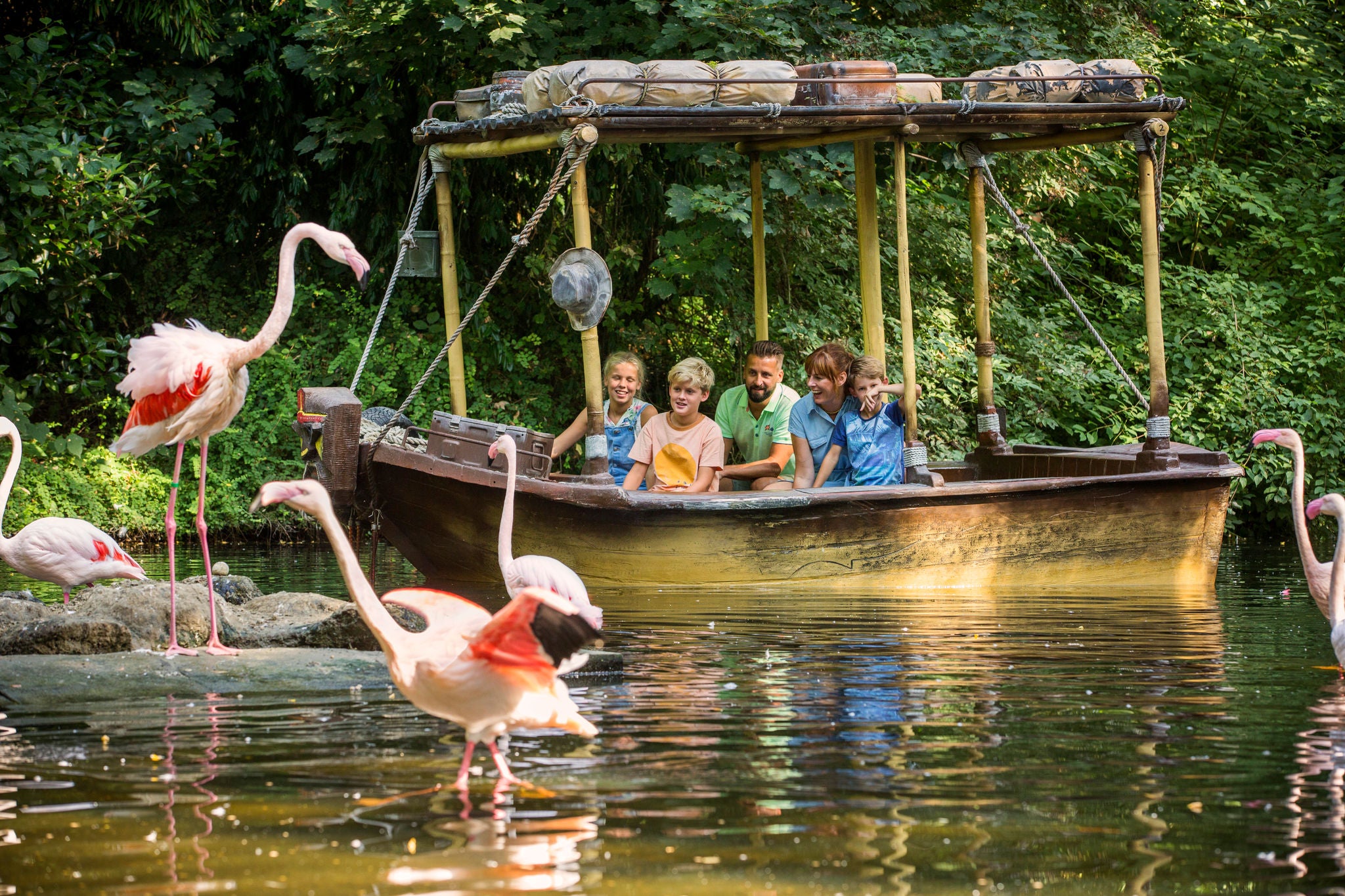 Gezin maakt een ritje in een boot op Jungle Mission en bewondert de Europese flamingo's.