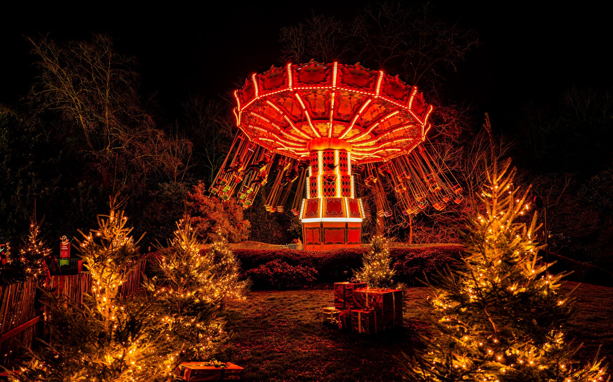 Flying carrousel tijdens de nacht met kerstbomen en cadeaus als kerstdecoratie.